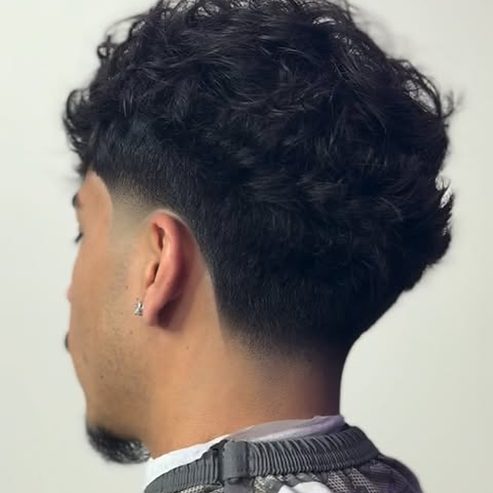 Mid tape fade — Curls kept full on top, tape line dropped clean around the back
